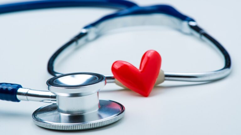 A stethoscope and a red heart-shaped object on a white surface.