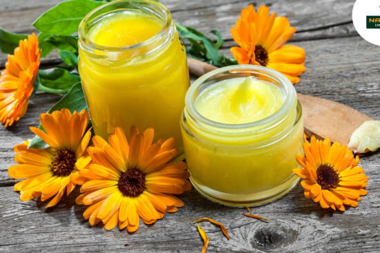 A bottle of calendula oil surrounded by fresh calendula flowers, highlighting its skin care benefits and health properties.