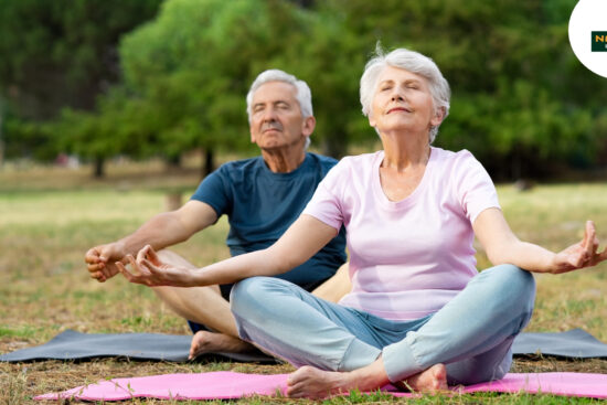 A men and old women doing peacefully yoga in the garden.