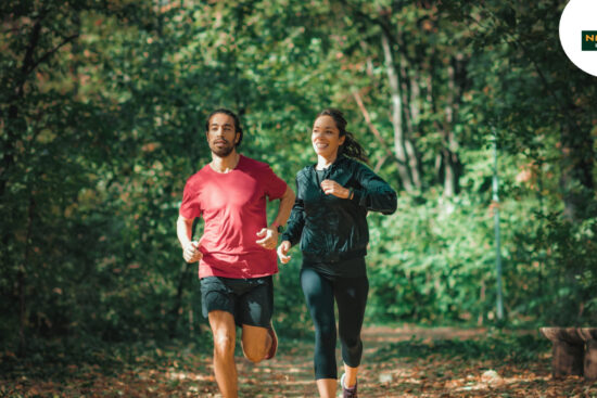 Two people running in a tranquil woodland, illustrating the health benefits of jogging versus walking.